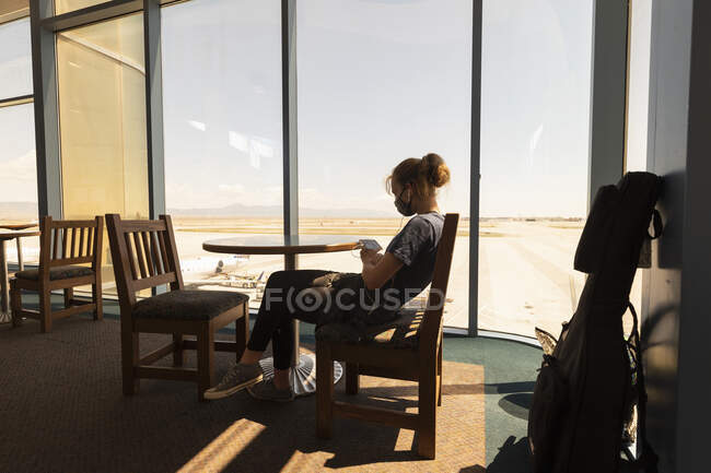 Teenagermädchen, das in einer Flughafenlounge auf ihr Smartphone wartet, Botsuana. — Stockfoto