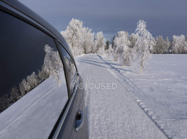 Coche con ventanas cerradas aparcado en una carretera nevada. - foto de stock