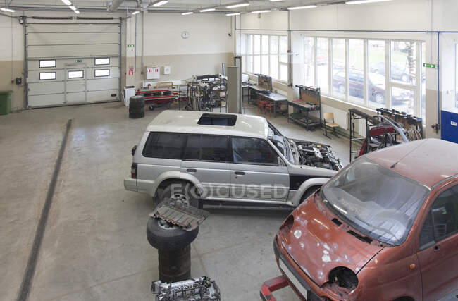 Dos mini furgonetas en un gran taller de reparación o garaje. - foto de stock