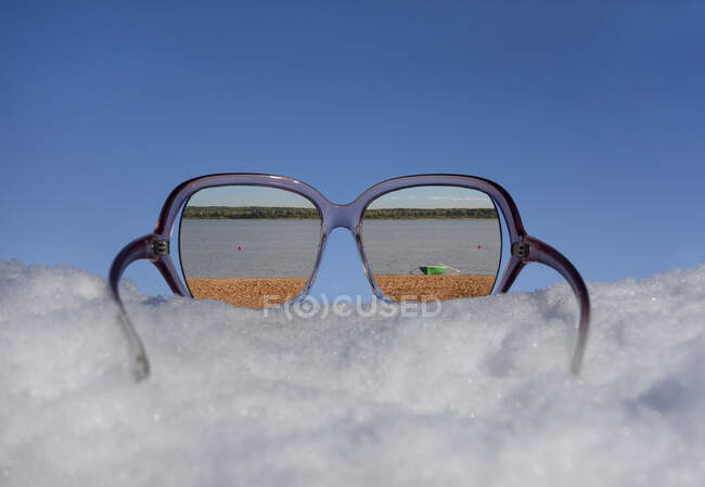 Playa y orilla del lago visto en la reflexión en gafas de sol en la nieve gruesa. - foto de stock