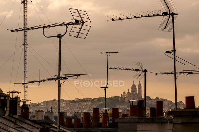 Sacre-Coeur Basilica viewed through television aerial antennae and apartment rooftops. — Stock Photo