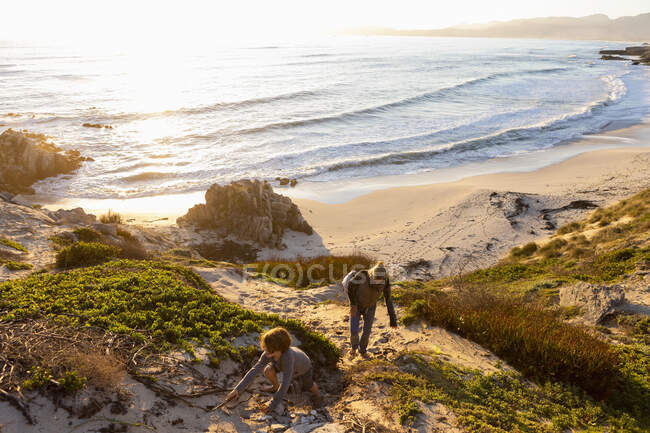 Молодий хлопчик і зріла жінка піднімається по скелі на заході сонця . — стокове фото