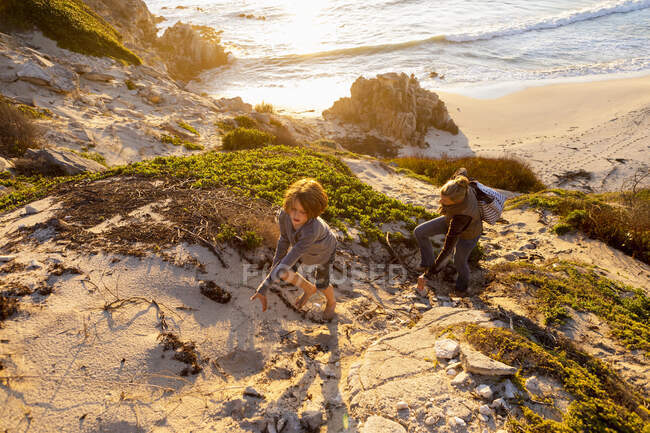 Giovane ragazzo e donna matura arrampicata su un sentiero scogliera al tramonto. — Foto stock