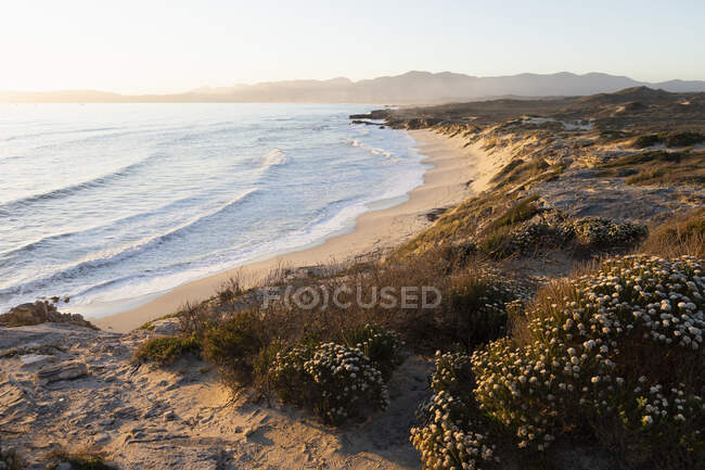 Vue depuis les falaises sur la plage de sable et les vagues se brisant sur le rivage. — Photo de stock