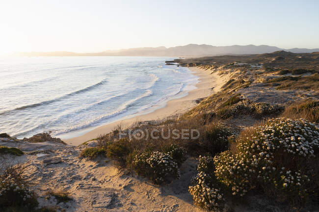 Vue depuis les falaises sur la plage de sable et les vagues se brisant sur le rivage. — Photo de stock