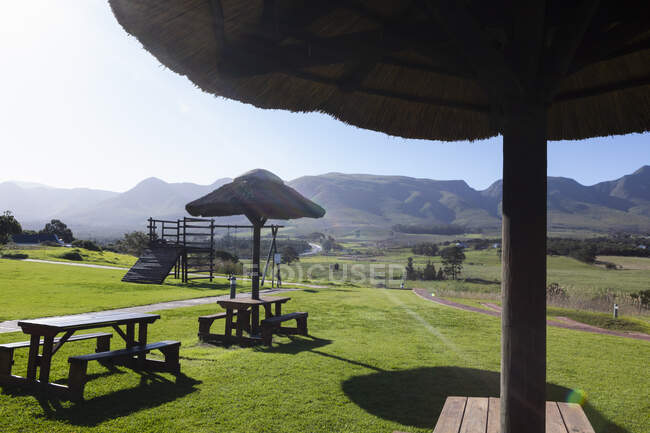 Un jardín con sombras y bancos de picnic, y una vista a la montaña - foto de stock