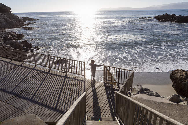 Un chico corriendo hacia la playa por unas escaleras - foto de stock