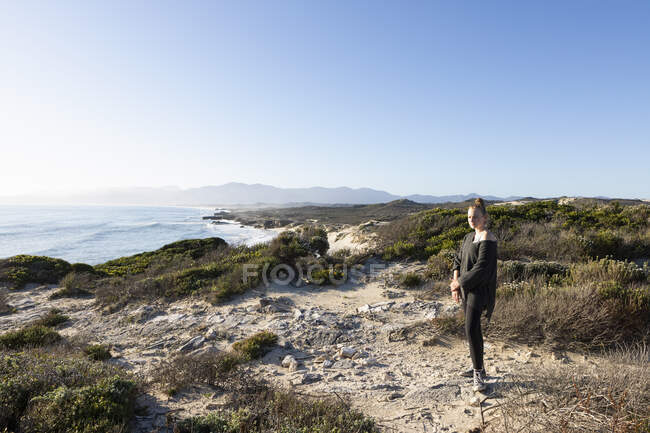 Teenage girl on a clifftop path above a beach — Stock Photo