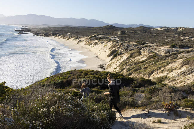 A teenager and her brother on a path down to a sandy beach — Stock Photo