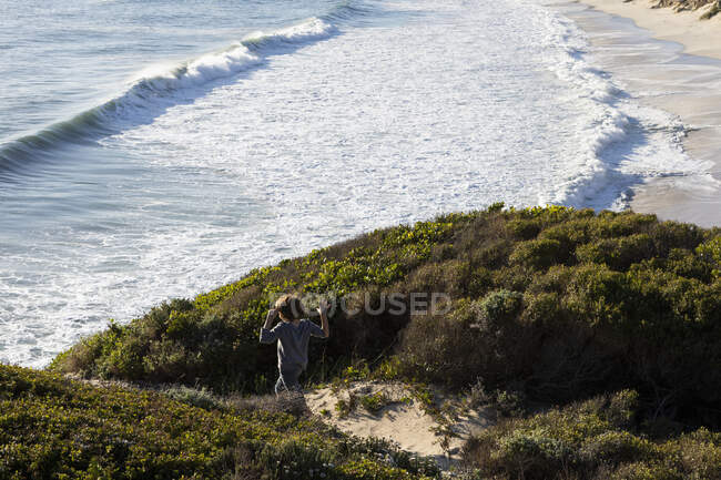 Um menino correndo excitadamente por um caminho até a praia — Fotografia de Stock