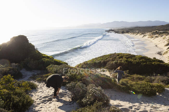 Una adolescente y su hermano en un camino a una playa de arena - foto de stock