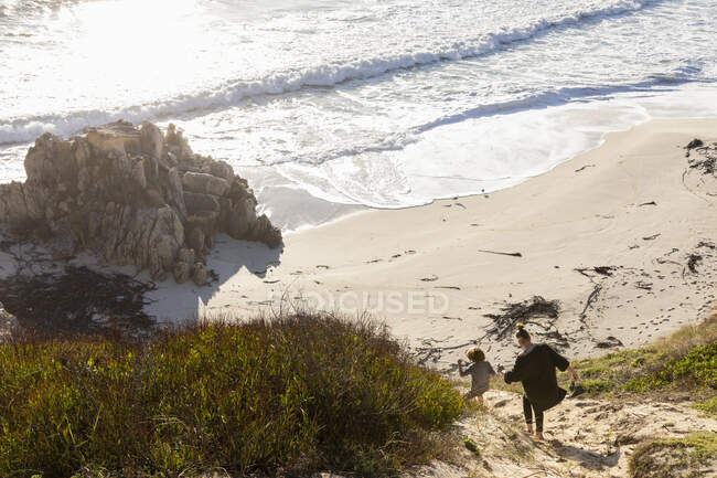 Дівчинка-підліток і її брат біжать по шляху до піщаного пляжу — стокове фото