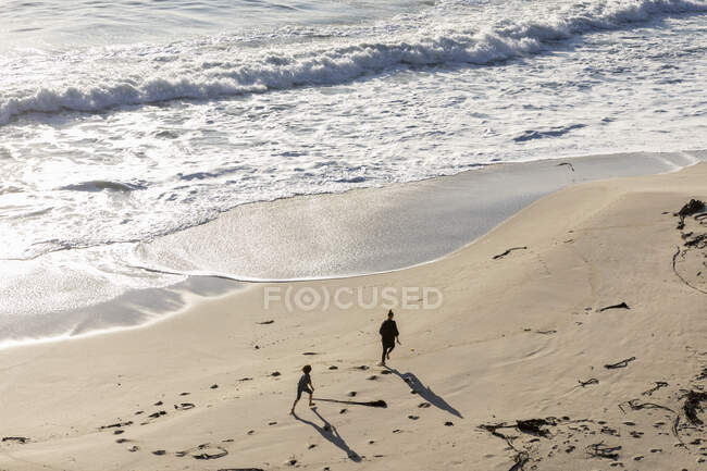 Двое детей бегают и оставляют следы на мягком песке пляжа — стоковое фото