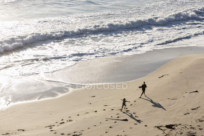Duas crianças correndo e deixando pistas na areia macia de uma praia — Fotografia de Stock