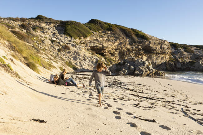 Família em uma praia de areia, menino caminhando através de areia macia — Fotografia de Stock