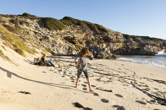 Сім'я на піщаному пляжі, хлопчик йде через м'який пісок — стокове фото