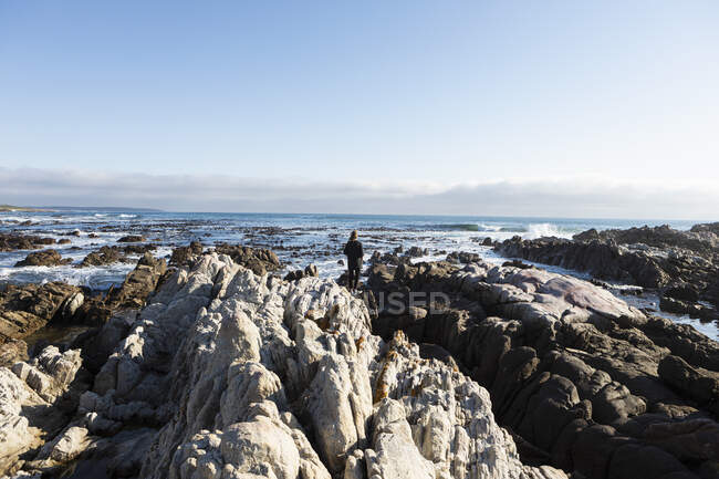 Дівчинка-підліток, що йде через зубчасті скелі, досліджує кам'яні басейни біля океану — стокове фото