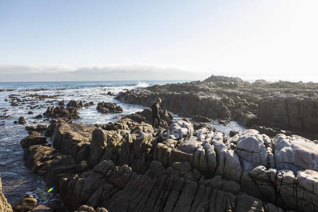 Девочка-подросток ходит по зазубренным скалам, исследует скальные бассейны у океана — стоковое фото