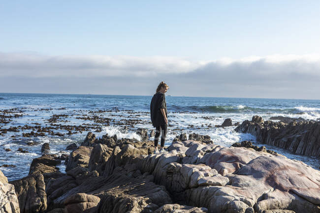 Adolescente caminhando através de rochas irregulares, explorando piscinas de rocha pelo oceano — Fotografia de Stock