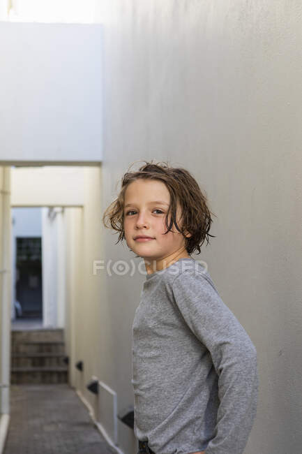 Портрет молодого хлопчика у вузькому провулку, який повертається, щоб подивитися на камеру — стокове фото
