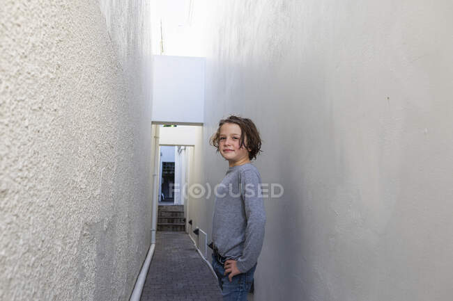 Portrait of young boy in a narrow alleyway, turning to look at the camera — Stock Photo