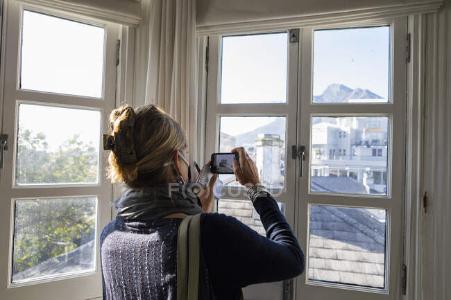 Mujer usando teléfono inteligente, mirando Table Mountain, Ciudad del Cabo - foto de stock