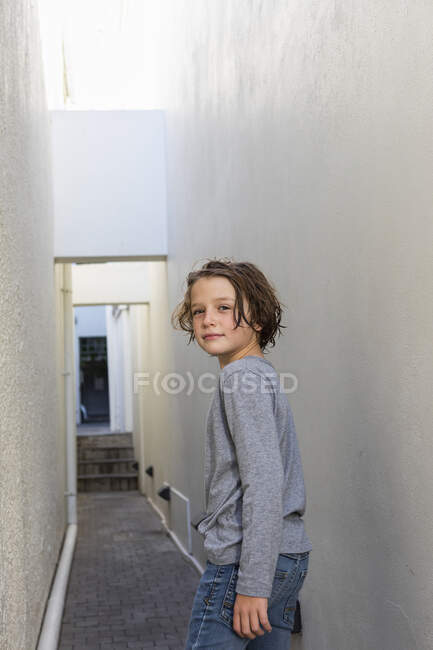 Porträt eines kleinen Jungen in einer Gasse, der sich umdreht, um in die Kamera zu schauen. — Stockfoto