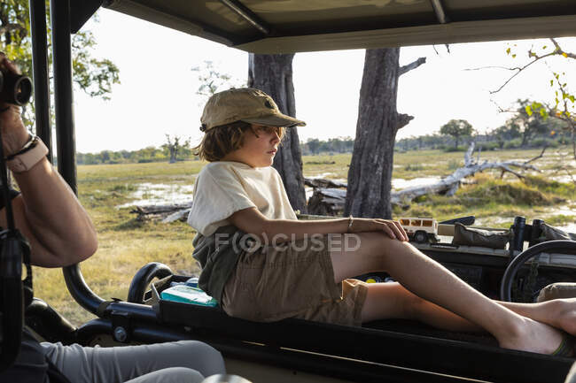 Un niño en un vehículo de safari mirando el paisaje - foto de stock