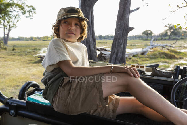 Un niño en un vehículo de safari mirando el paisaje - foto de stock