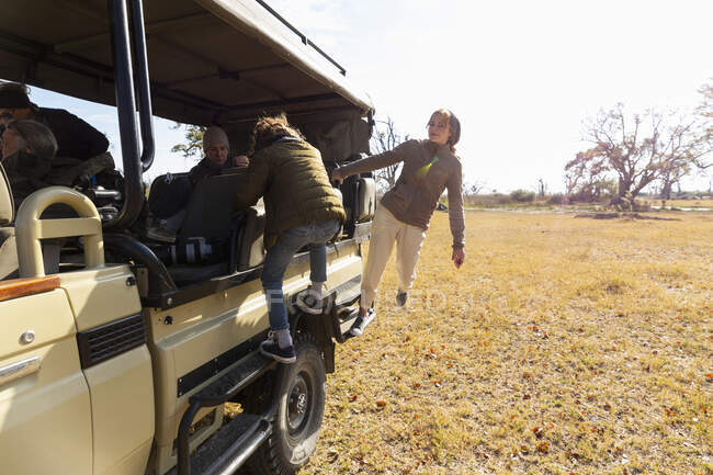 Une adolescente et un jeune garçon grimpant dans une jeep safari. — Photo de stock