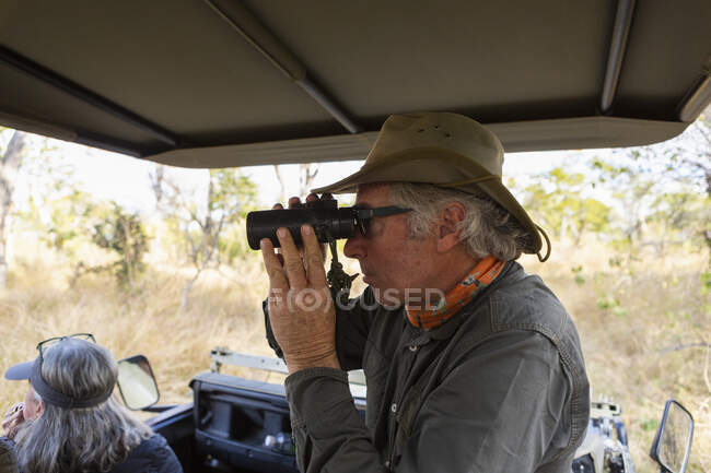 Safari guide using binoculars in a jeep with a family — Stock Photo