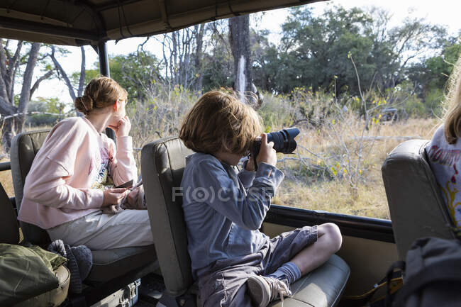 Giovane ragazzo utilizzando una fotocamera in una jeep safari — Foto stock