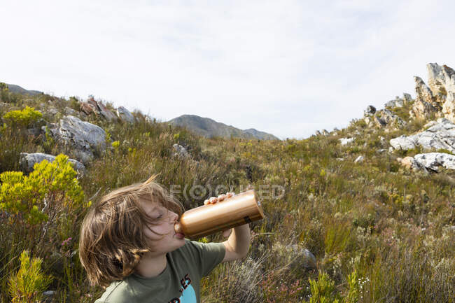 Junge auf Naturlehrpfad und trinkt aus Wasserflasche. — Stockfoto