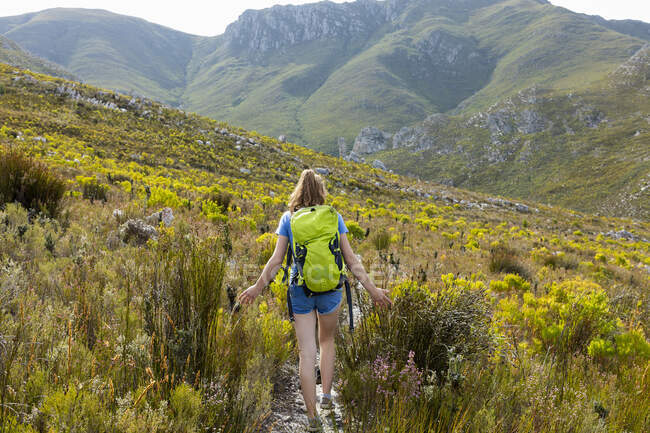 A teenage girl walking along a path in the mountains with a backpack — Stock Photo