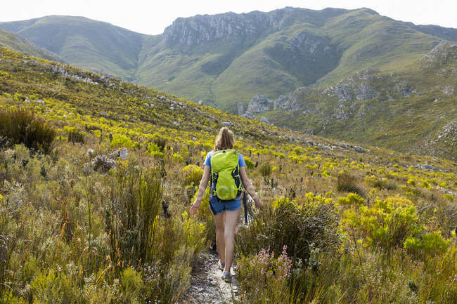 Дівчинка-підліток, що йде стежкою в горах з рюкзаком — стокове фото