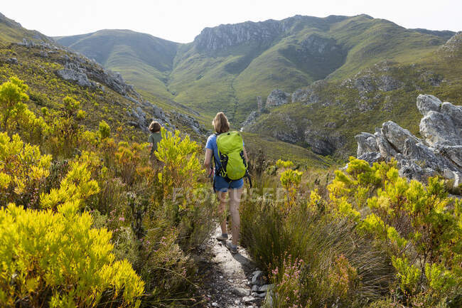 Uma adolescente caminhando ao longo de um caminho nas montanhas com uma mochila — Fotografia de Stock