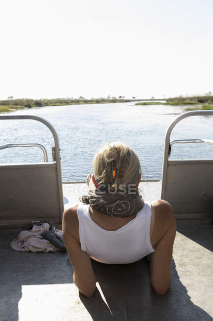 Una mujer relajándose en un barco en una vía navegable - foto de stock