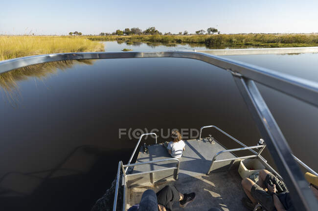 Ein Junge auf einem Motorboot auf einer Wasserstraße im Okavango-Delta — Stockfoto