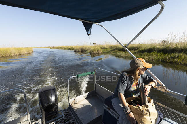 Жінка з водяною колбою, що сидить на моторному човні, що подорожує по водному шляху . — стокове фото