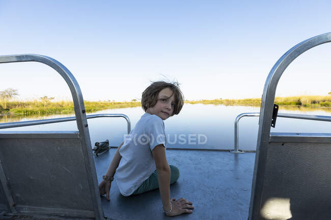 Хлопчик на моторному човні подорожує вздовж водного шляху в дельті Окаванго. — стокове фото