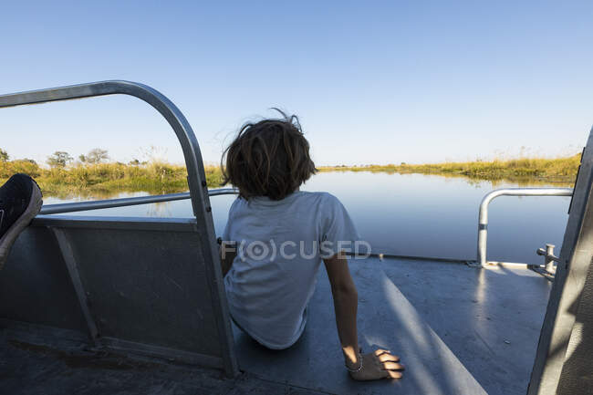 Ein Junge auf einem Motorboot auf einer Wasserstraße im Okavango-Delta — Stockfoto