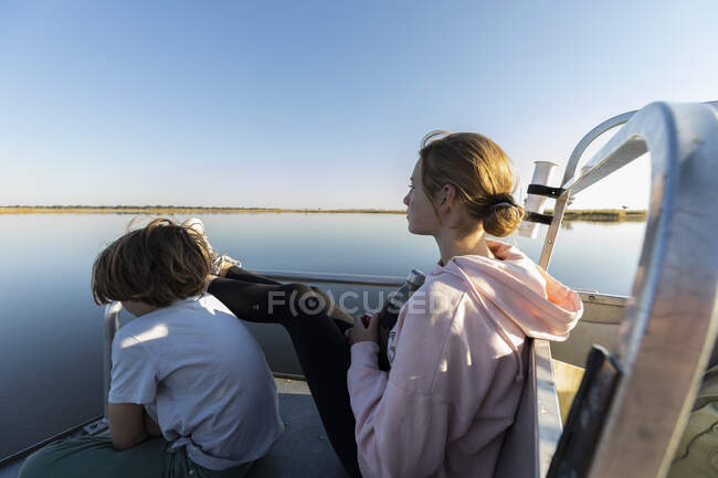 Duas crianças em um barco, um menino e sua irmã adolescente olhando para fora sobre a água — Fotografia de Stock