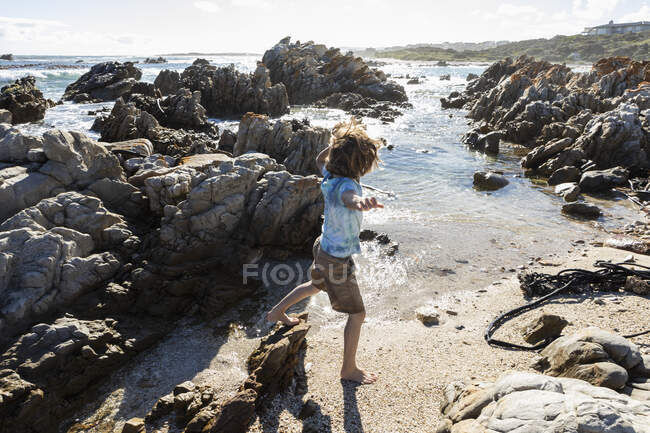 Eight year old boy exploring a rocky beach — Stock Photo