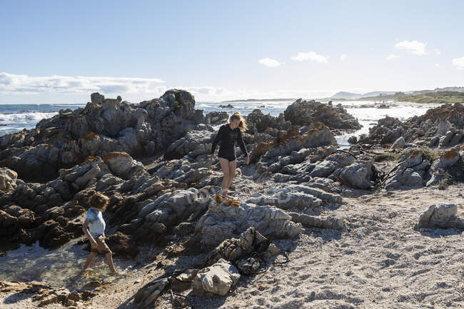 Двоє дітей, дівчинка-підліток і восьмирічний хлопчик, що досліджує зубчасті скелі і скелі на пляжі . — стокове фото