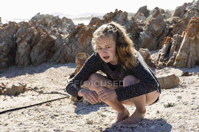 Девочка-подросток собирает ракушки на песчаном пляже — стоковое фото