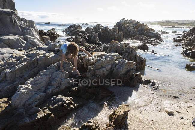 Achtjähriger Junge erkundet felsigen Strand — Stockfoto
