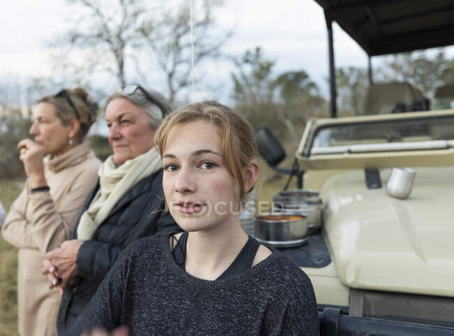 Three generations of women, a grandmother, mother and teenage girl by a safari jeep — Stock Photo