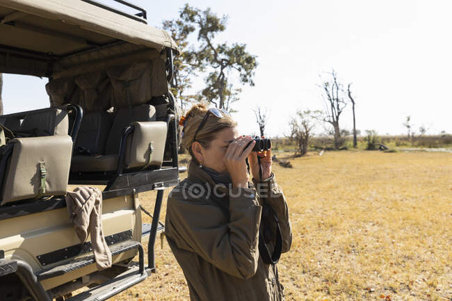 Woman using binoculars,Okavango Delta, Botswana — Stock Photo