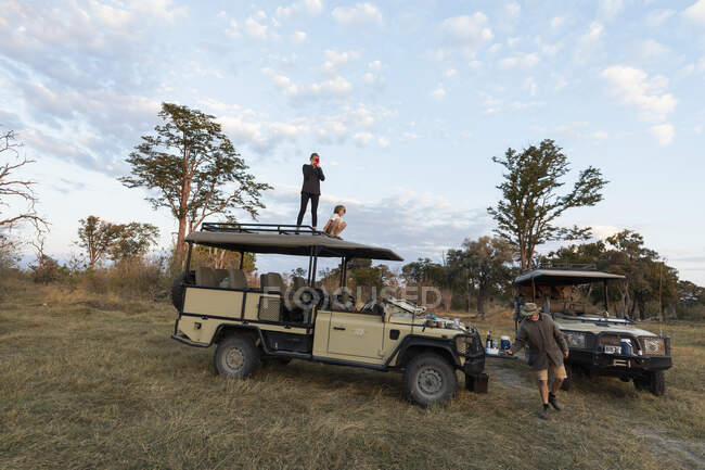 Dos niños en el techo de un vehículo de safari en una unidad de juego del amanecer - foto de stock