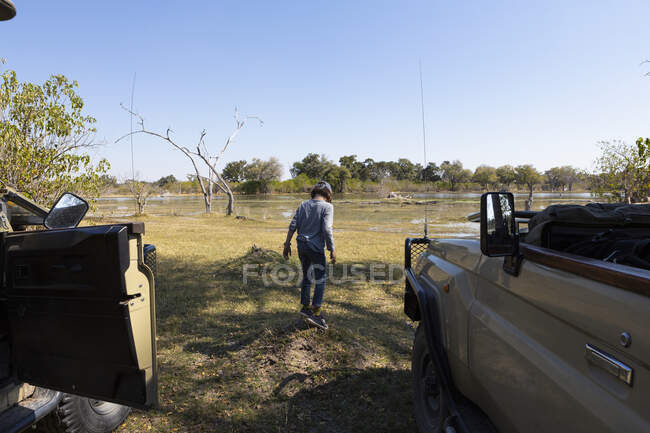 A boy stretching his legs by a safari jeep in a wildlife reserve — Stock Photo